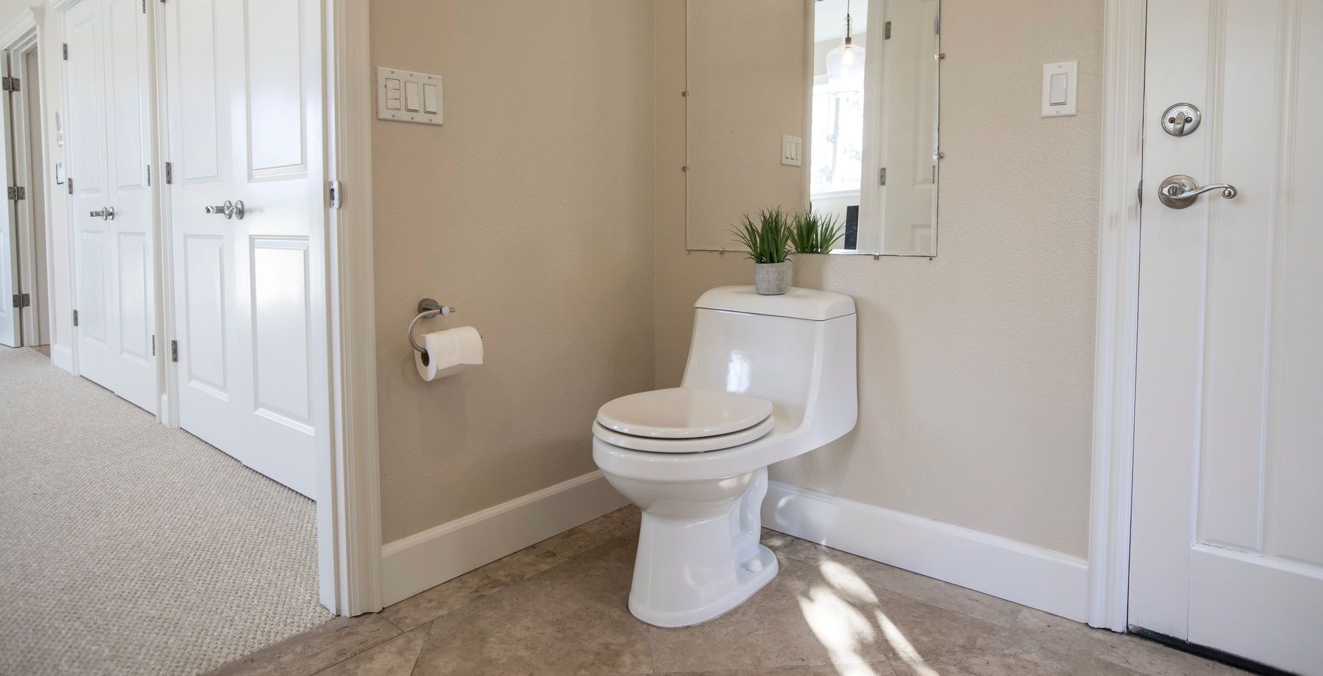 Contemporary bathroom design featuring a white toilet, mirror, and decor.