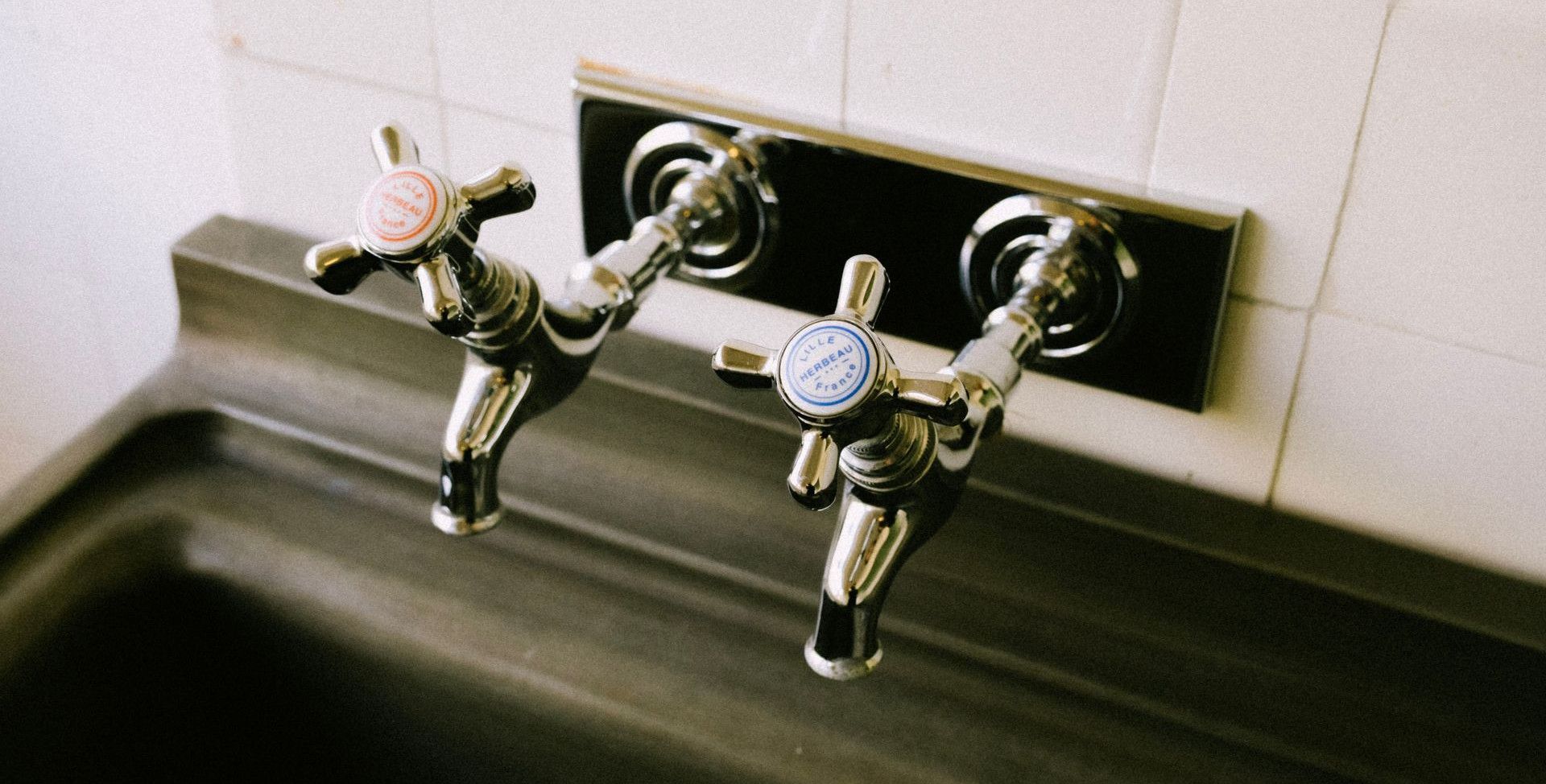 Detailed view of chrome sink faucets with classic hot and cold labels in a kitchen setting.